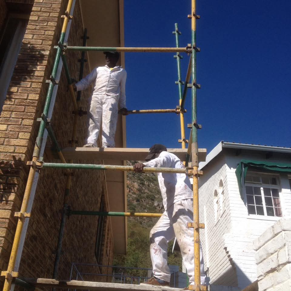 Team painting exterior on scaffolding